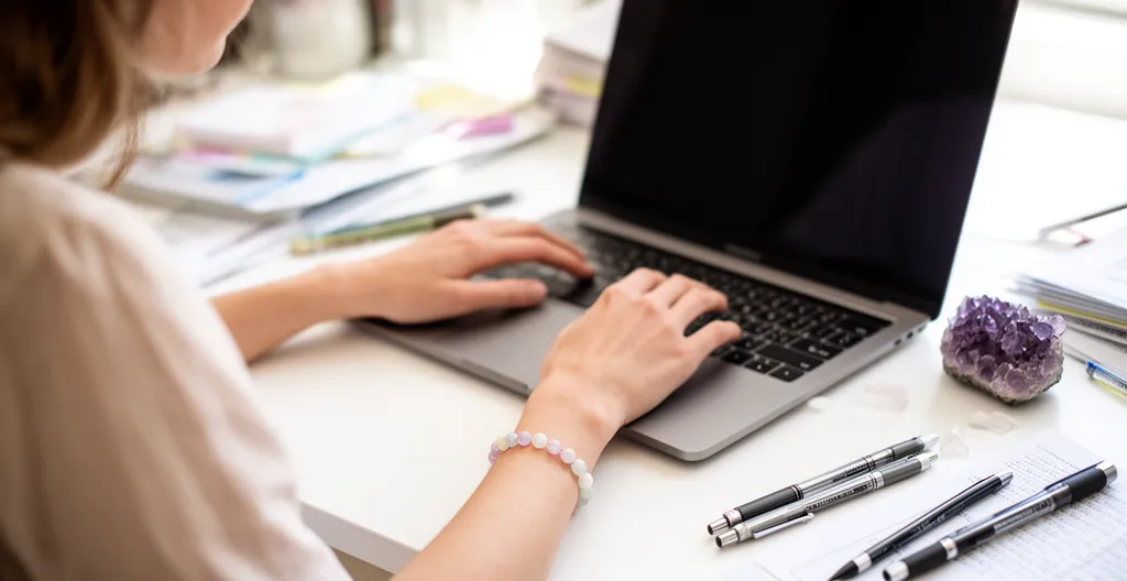 Femme portant un bracelet en pierres naturelles tout en travaillant sur ordinateur